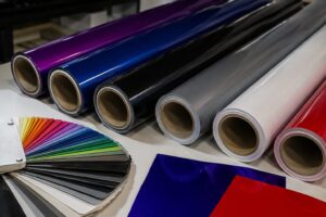Close-up of colourful cast and calendared vinyl rolls and sample swatches arranged on a workshop table.